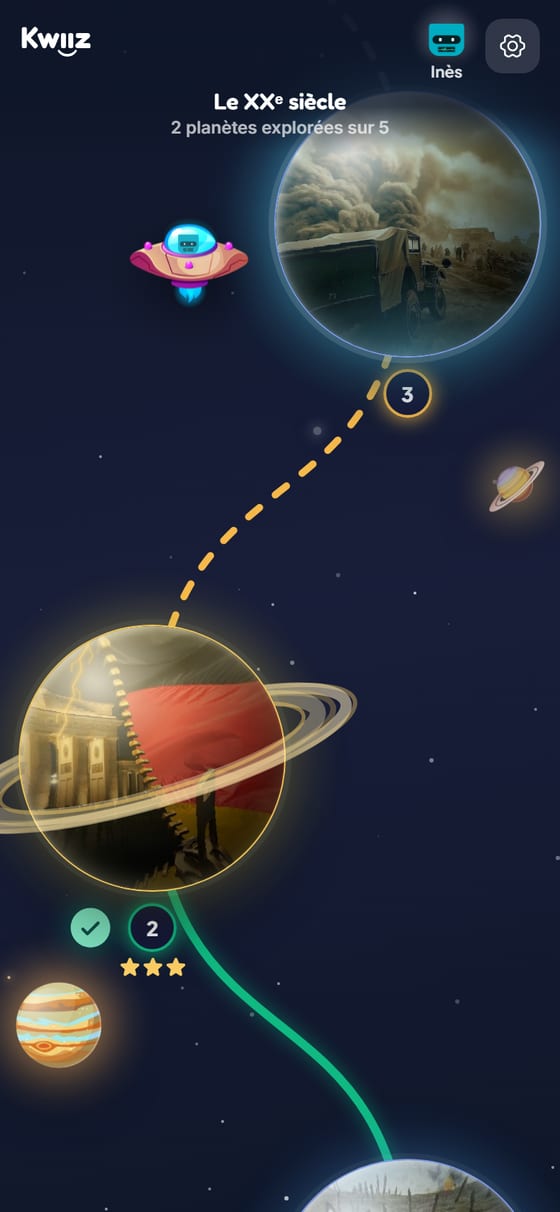 Le parcours d'Inès dans l'expédition « Le XXᵉ siècle » : « 2 planètes explorées sur 5 », la planète 2 « Les dictatures totalitaires » réussie avec ses trois étoiles et sa coche verte, un chemin vert derrière elle, et la soucoupe d'Inès posée devant la planète 3